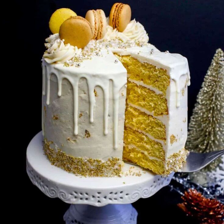 A sliced eggnog cake topped with icing and macarons, baked after reading these Christmas cake recipes