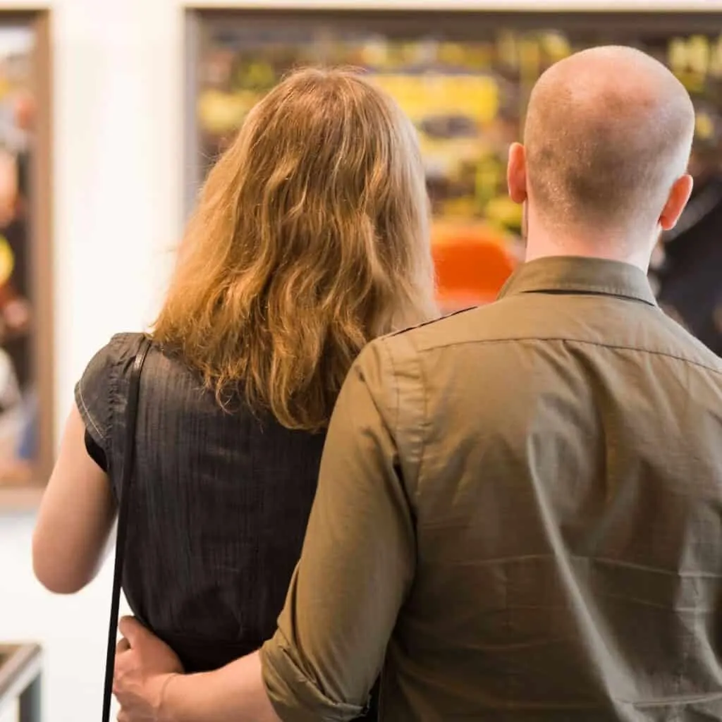 A couple looking at an artwork in an art gallery, after reading these Creative anniversary ideas