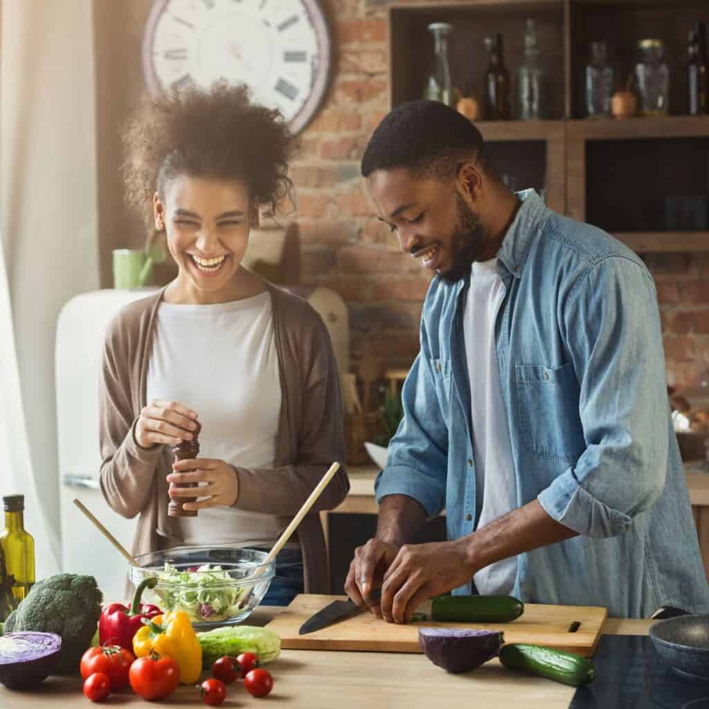 A happy couple cooking together after reading these 10 tips for a happy marriage