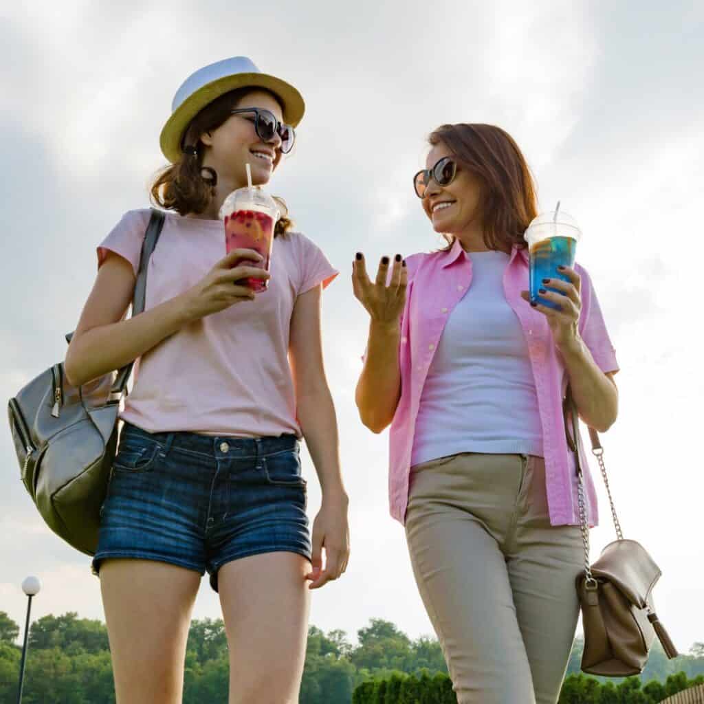A mother walking along with her daughter, asking these would you rather questions while enjoying their cup of juices together