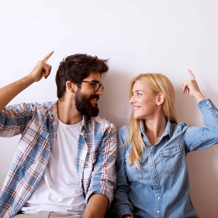A happy couple looking at each other while pointing upwards: He said she said questions