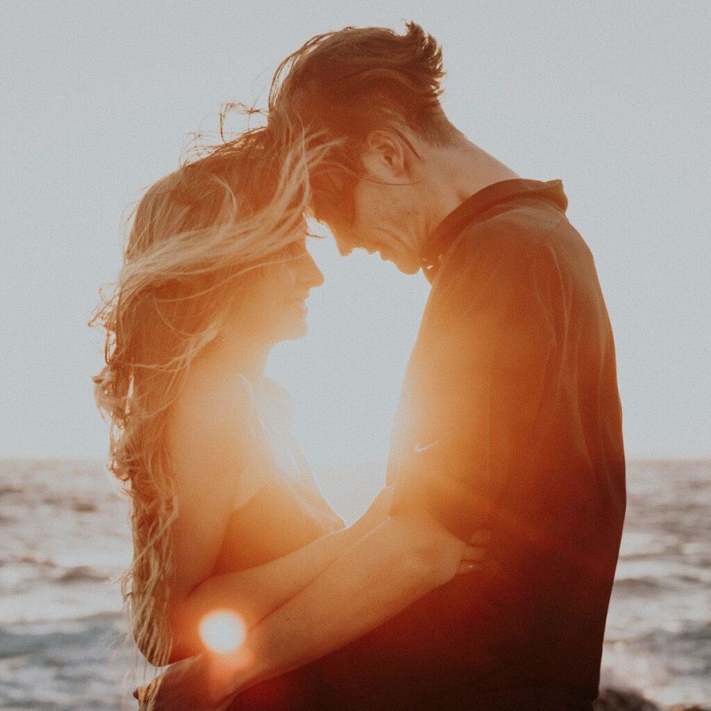A couple pressing their foreheads together, with a beautiful sunset on the background, making time for magical moments after reading these 10 tips for a happy marriage
