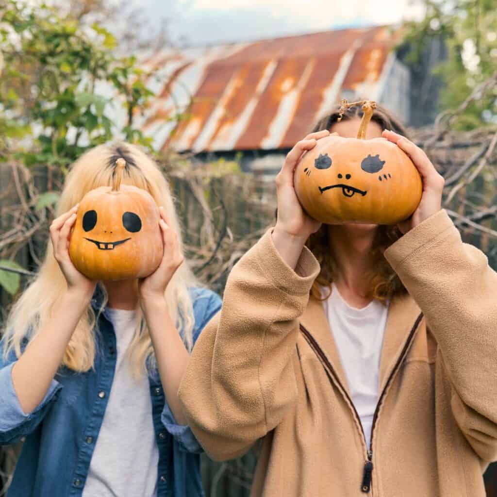 A teen couple carrying a pumpkin with face designs, after reading these Fall date ideas for teens