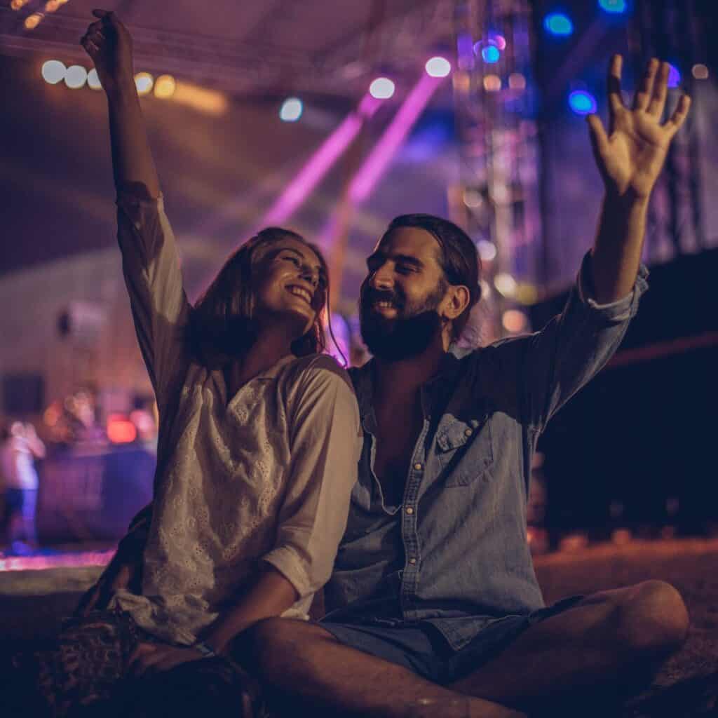 A couple raising their hands while they are at a concert, after reading these 10 tips for a happy marriage