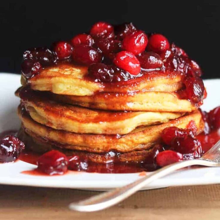 A plate of eggnog pancakes with cranberry maple syrup made after reading these Christmas breakfast ideas