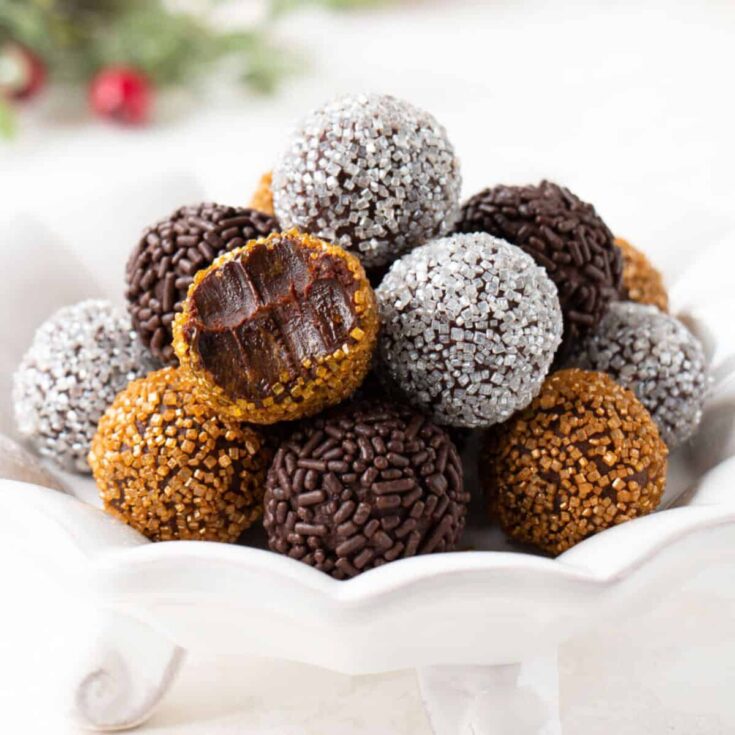 A bowl of homemade chocolate truffles with silver, brown, and gold sprinkles, made after reading these Christmas truffle ideas