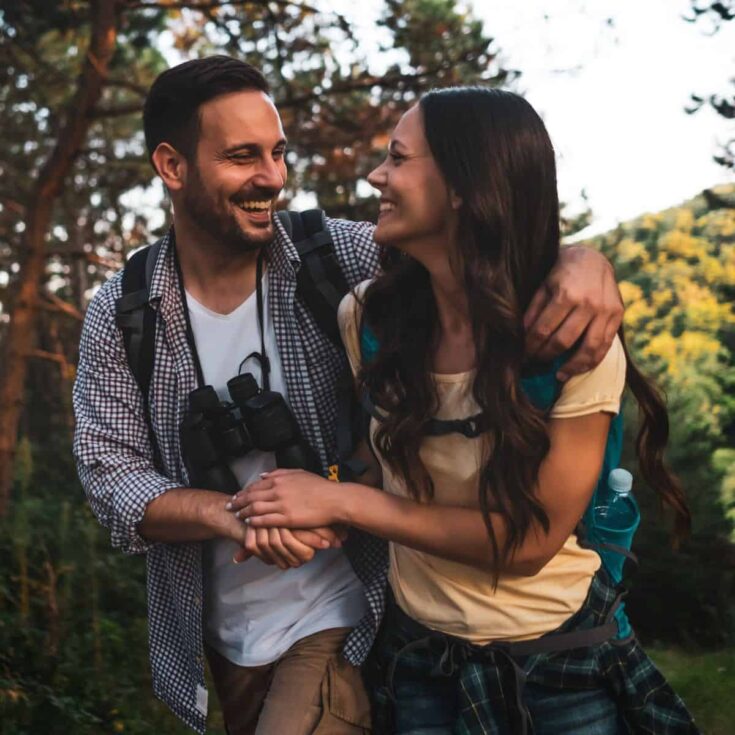 A happy couple walking in the middle of the forest after reading this How to create a couples scavenger hunt
