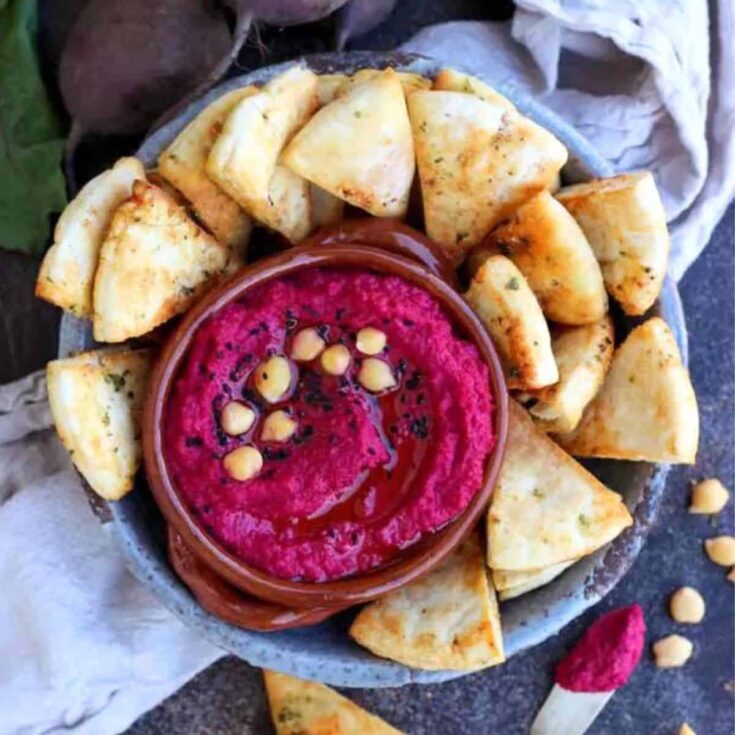 A bowl filled with roasted beet hummus with pita chips made after reading these Valentines appetizers