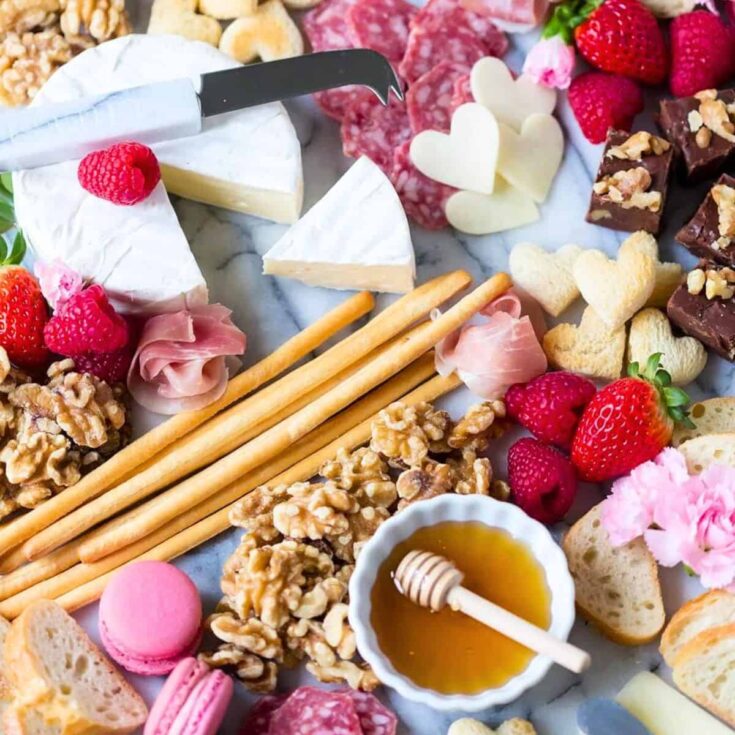 Valentines charcuterie board filled with nuts, strawberries, bread, cheese, and more, amde after reading these Valentines appetizers