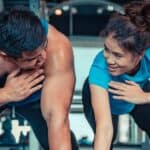 A happy couple looking at each other as they exercise in the gym, with the text overlay after reading these Fitness dates ideas for active couples
