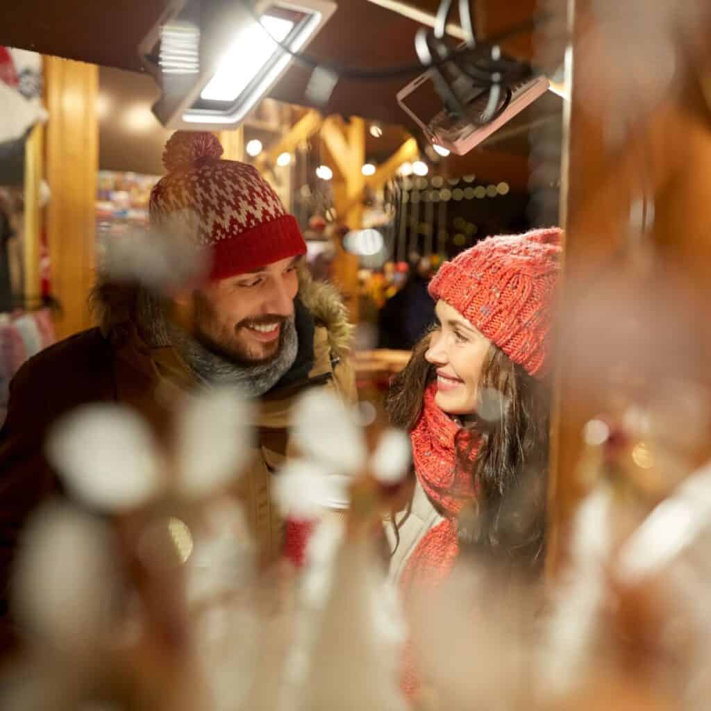 A happy couple at a Christmas market after reading these Christmas date ideas