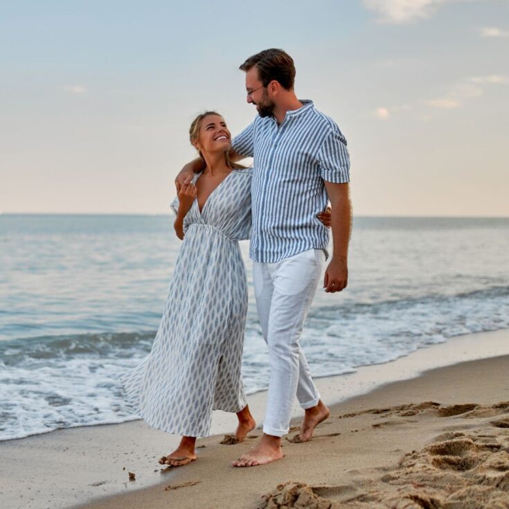 A happy couple walking together at the beach, after reading these beach love quotes