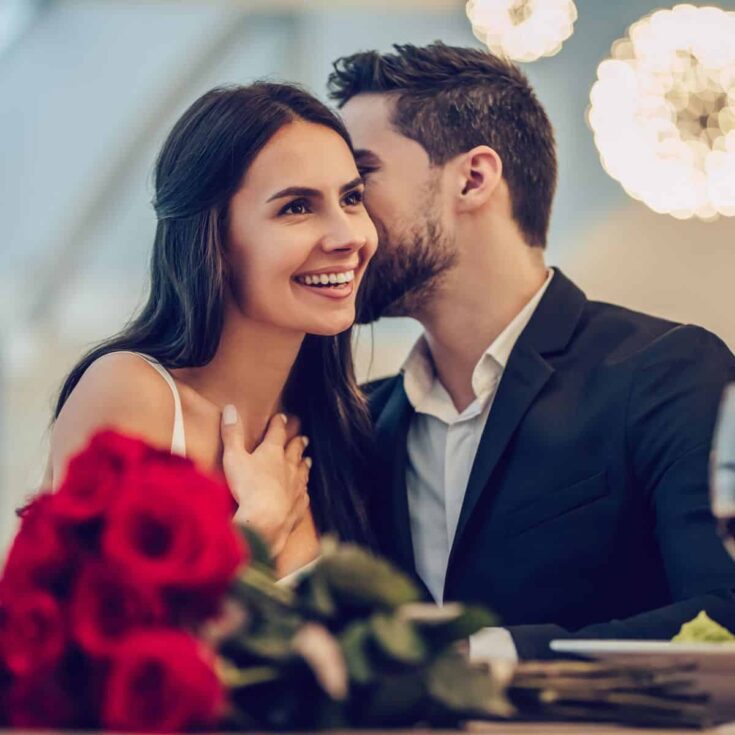 A couple in an expensive date, the man whispering something to the woman
