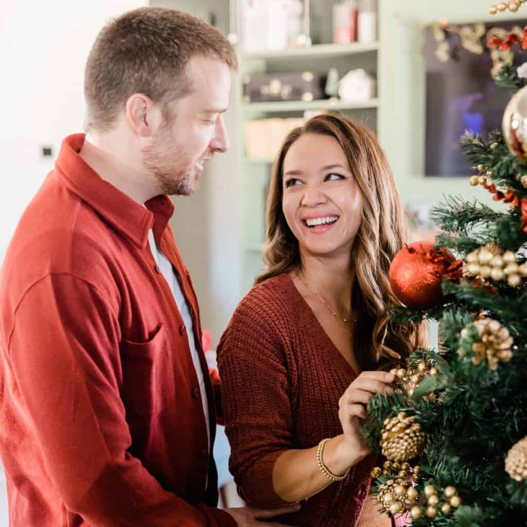 A happy couple decorating their Christmas tree after reading these Christmas date ideas