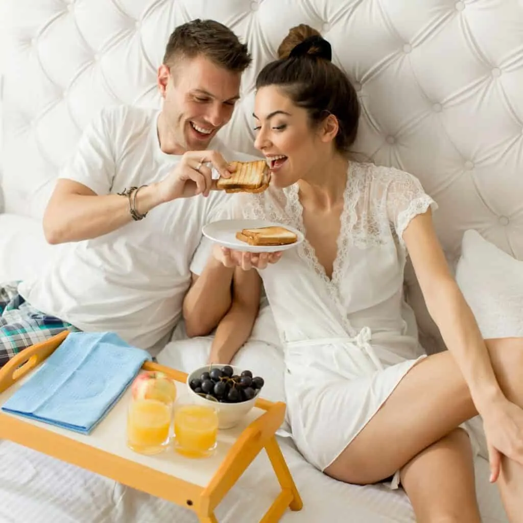 A woman being fed with breakfast on bed after winning a bet