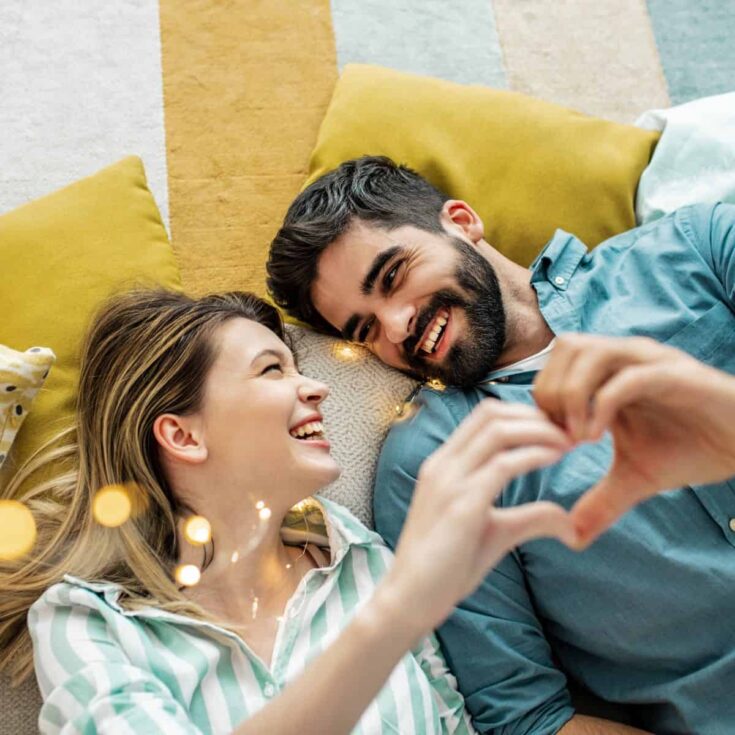 Coupe smiling and making heart shape with hands playing truth or dare questions for couples