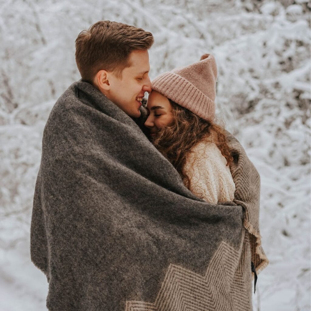 A couple snuggled together in a blanket: How to survive your family Christmas