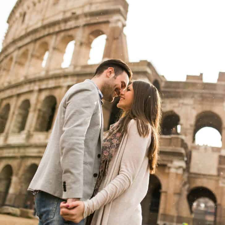 A happy couple facing each other closely as they traveled in Rome and saw the Colosseum, after reading these Couple travel quotes
