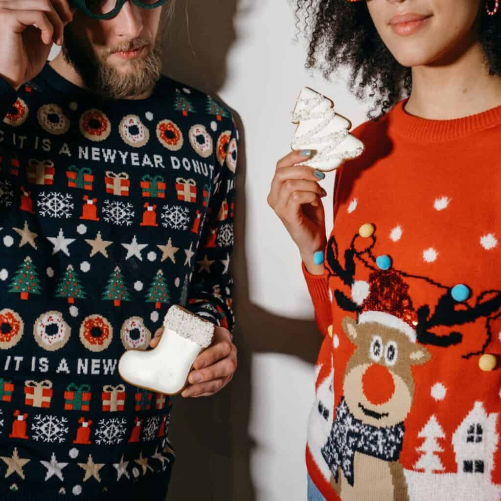 A couple holding Christmas cookies while wearing Christmas sweaters: How to survive your family Christmas