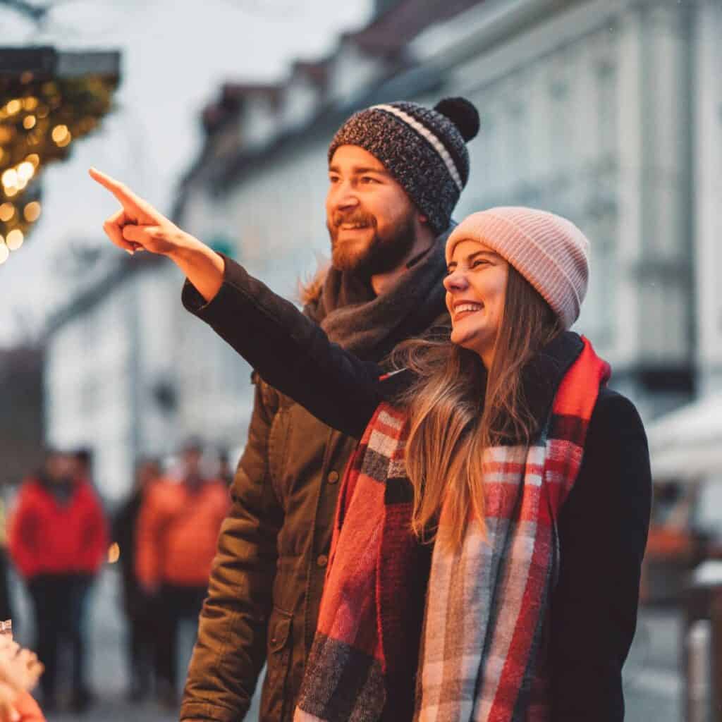 A happy couple in a Christmas market rewarding themselves after surviving their family Christmas