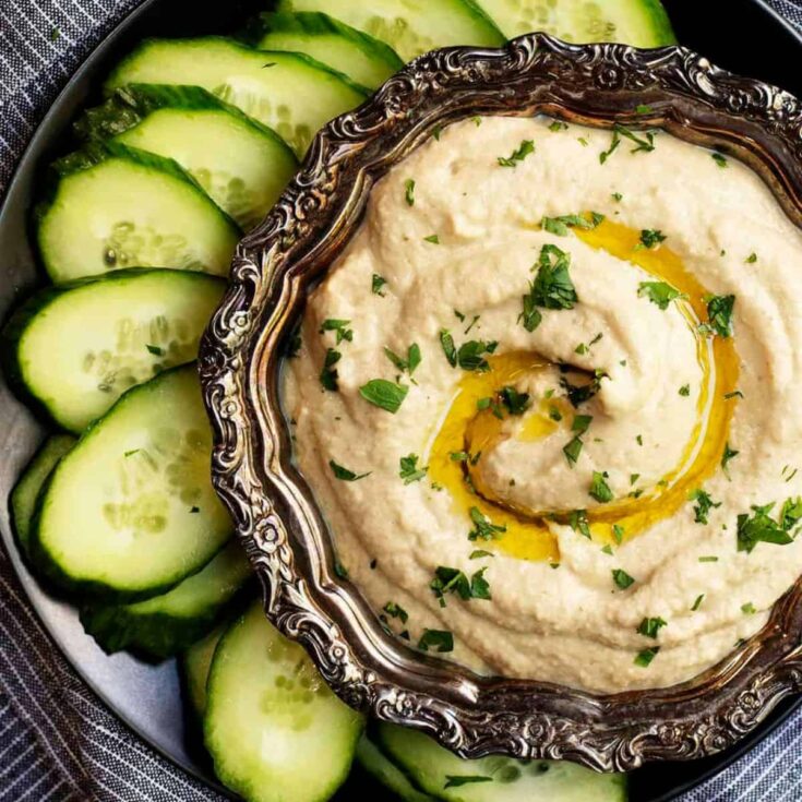 A bowl of bacon dip with cream cheese surrounded with sliced cucumbers