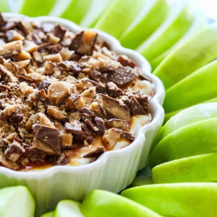 A bowl of caramel apple dip sided with sliced green apples