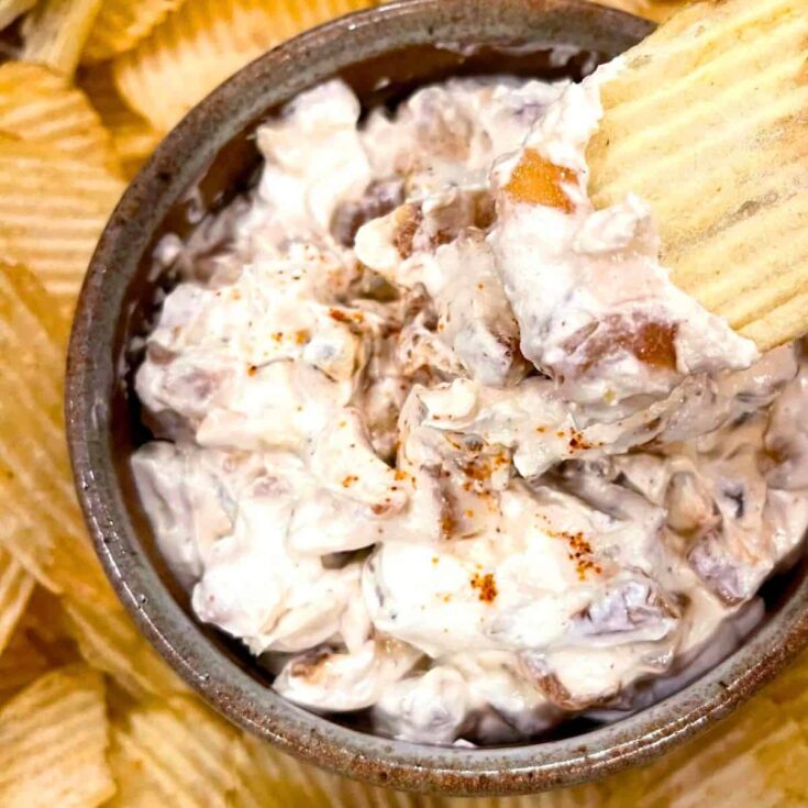 A bowl of caramelized onion dip with potato chips