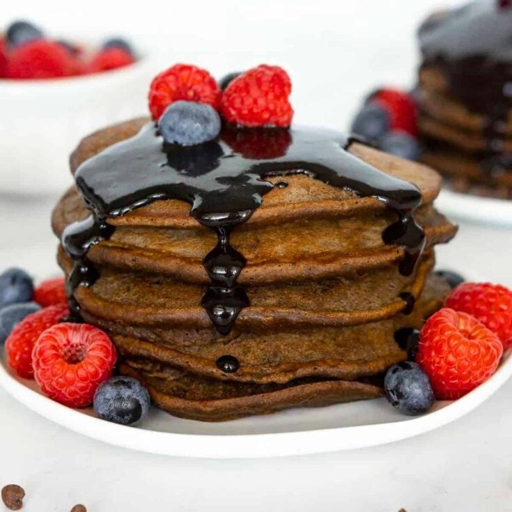 Chocolate protein pancakes with chocolate sauce, raspberries, and blueberries