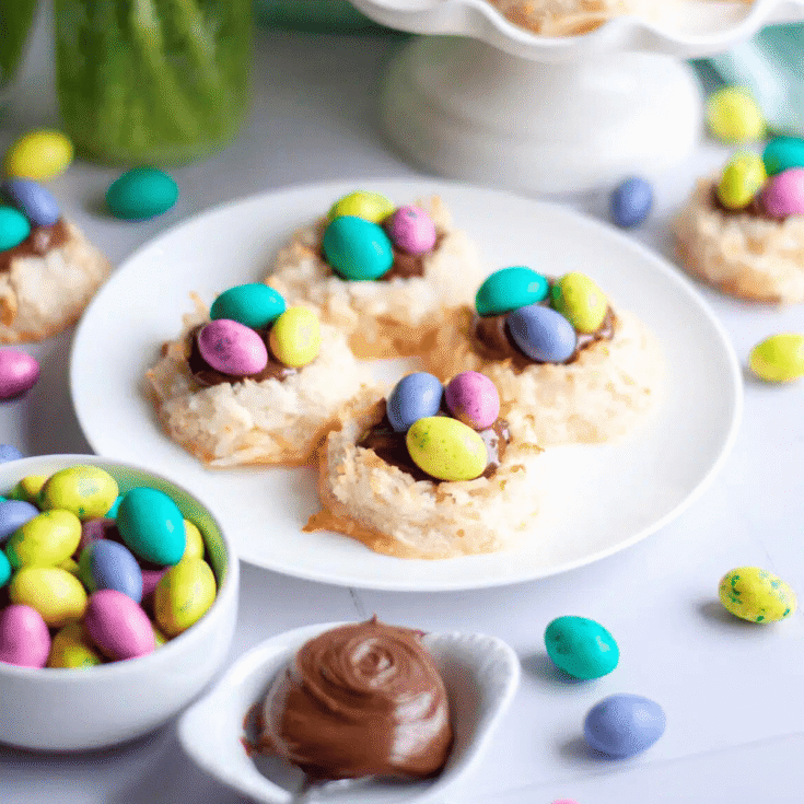 A plate of coconut macaroon nests topped with colorful easter eggs