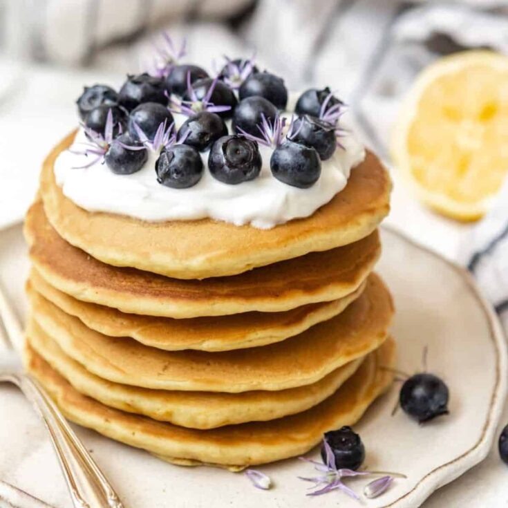 Fluffy lemon pancakes topped with whipped cream and blueberries