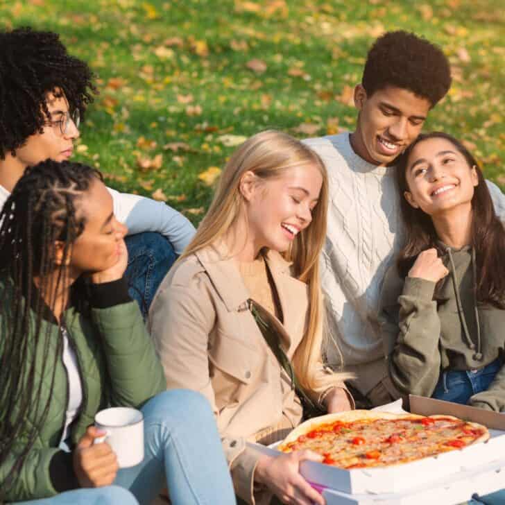 A group of teens having a pizza picnic after reading these fun and affordable group date ideas for teens