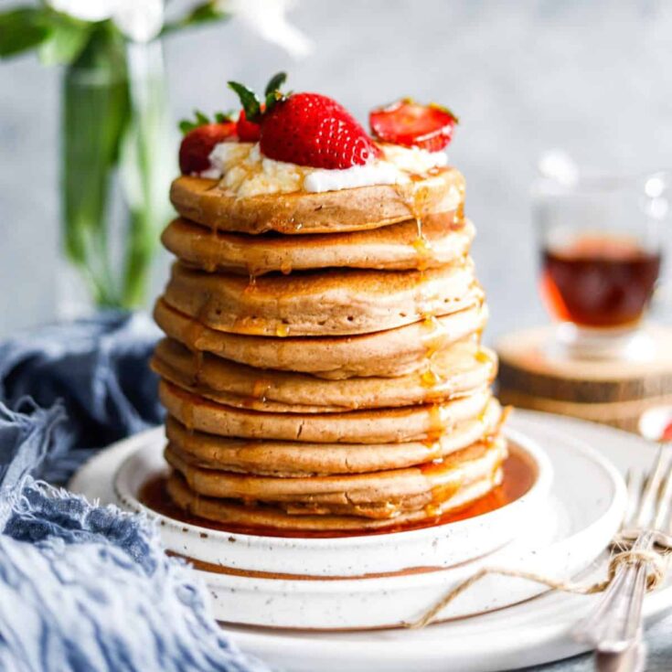 A stack of old fashioned buttermilk pancakes topped with strawberries