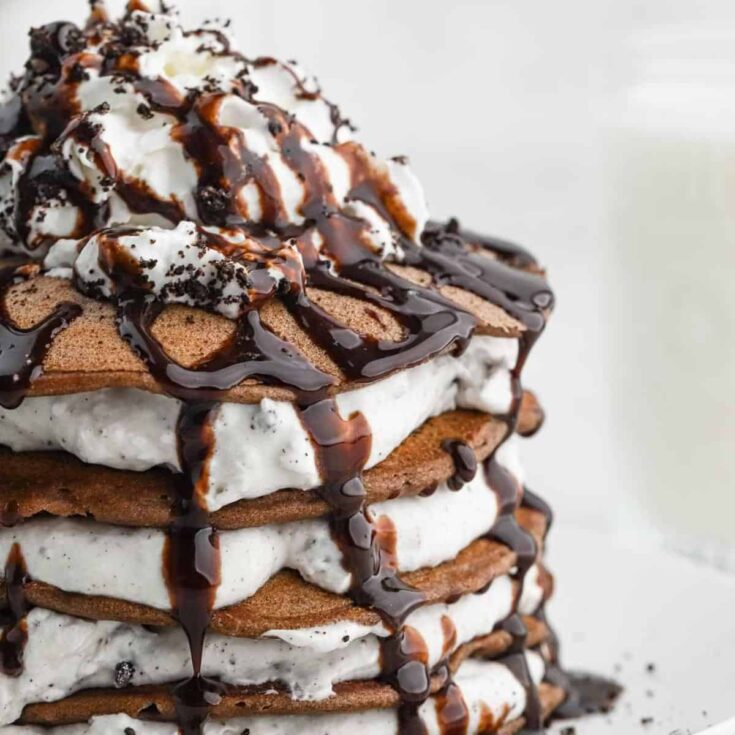 Oreo pancakes topped with whipped cream and chocolate syrup