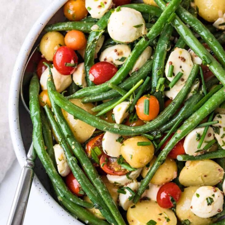 A bowl of tangy green bean potato and tomato salad