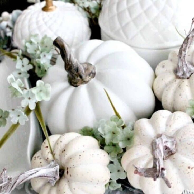 a white Fall centerpiece with acorn vases and white pumpkins