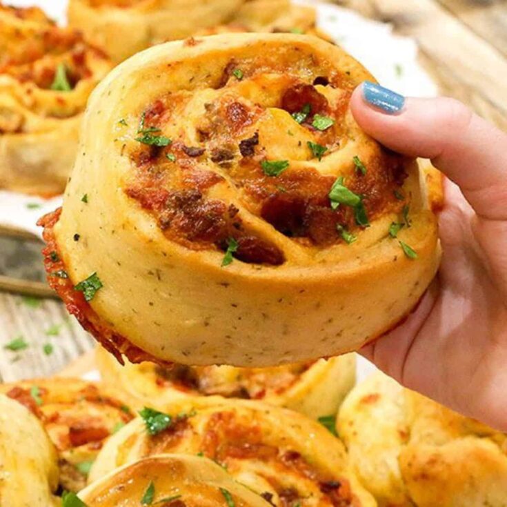 A person holding a meat lovers pizza pinwheel