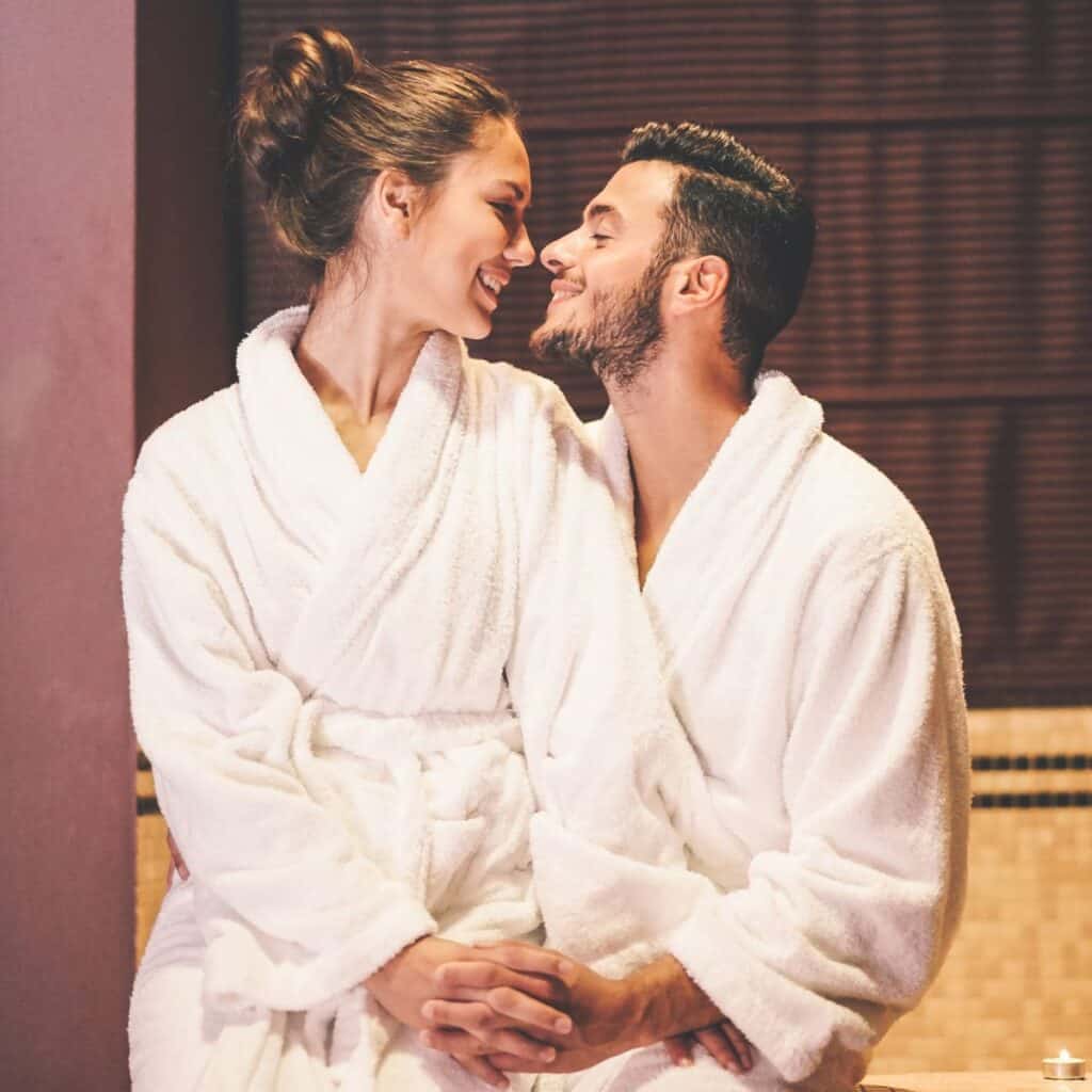 A couple in bathrobes, looking at each other happily
