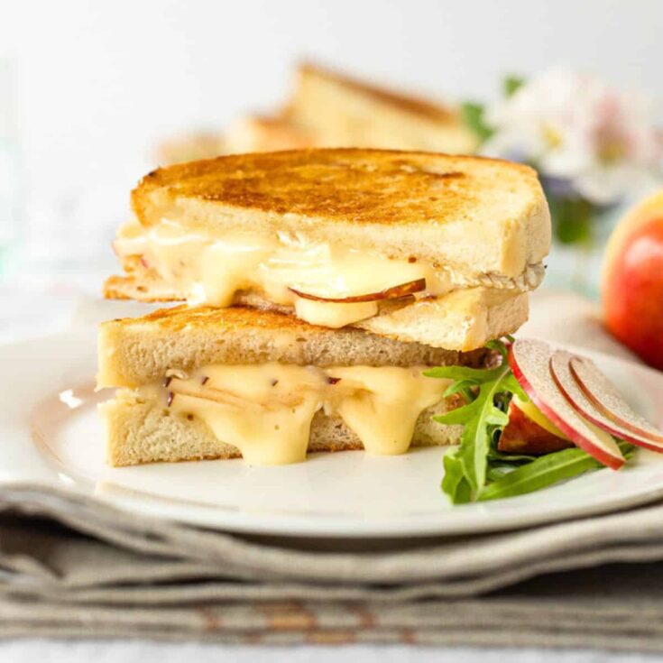 A plate of brie and apple with hot honey grilled cheese sandwich