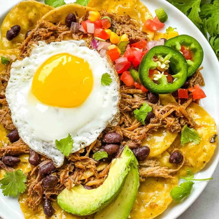 A plate of pork carnitas green chilaquiles with eggs