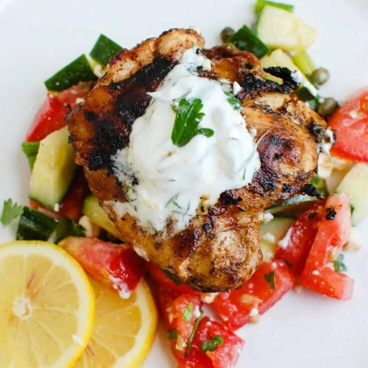 A plate of Greek marinated chicken with tzatziki sauce