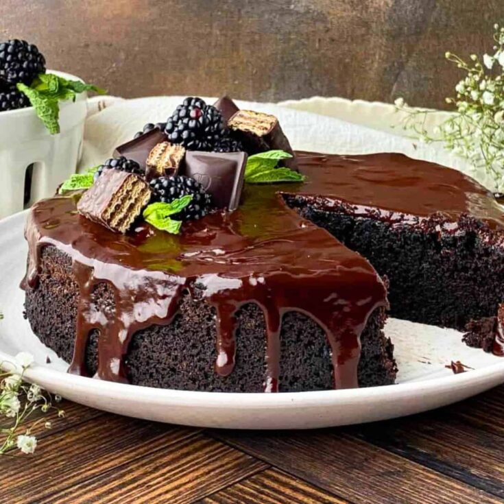 Chocolate ganache cake topped with chocolate wafer and blackberries