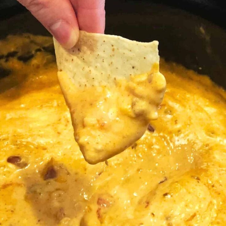 A chip dipped in crockpot chili cheese dip