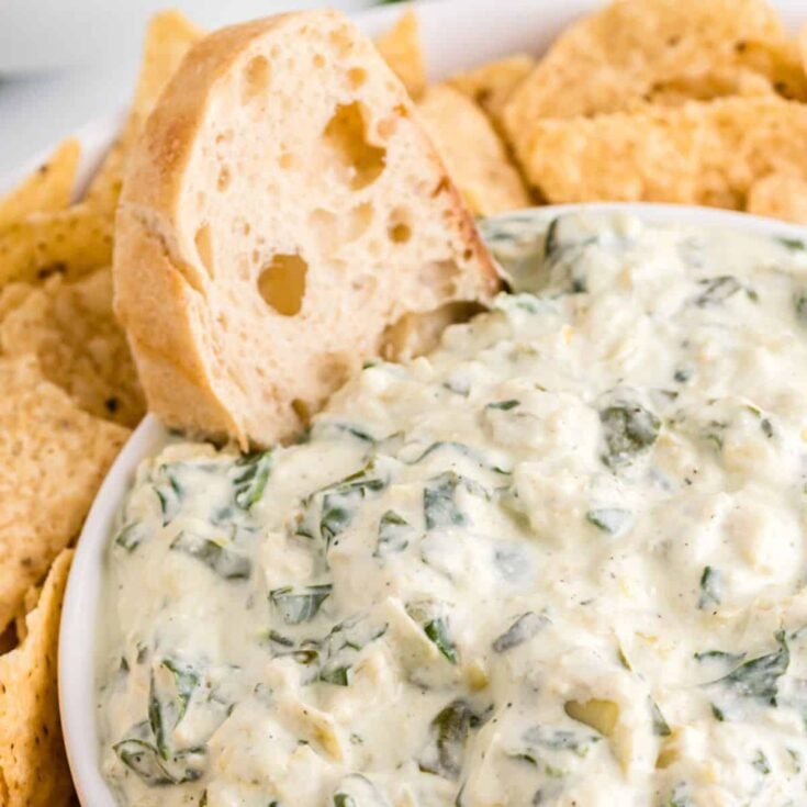 Crockpot spinach artichoke dip with chips and bread on the side