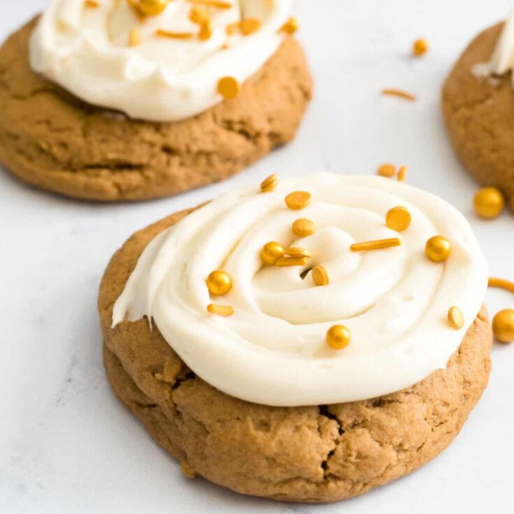 Crumbl gingerbread cookies topped with cream and gold sprinkles