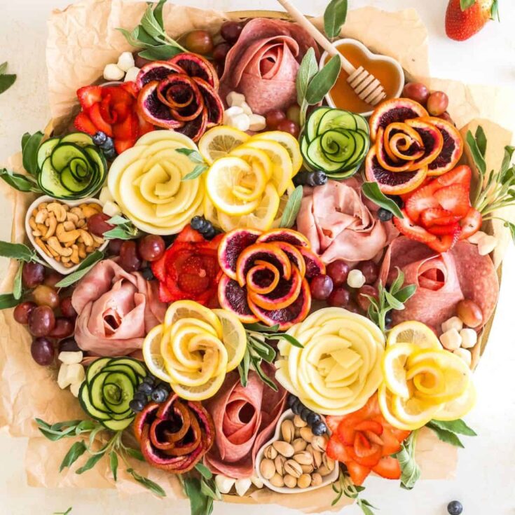 Charcuterie board with meat, fruits, and vegetables shaped like flowers