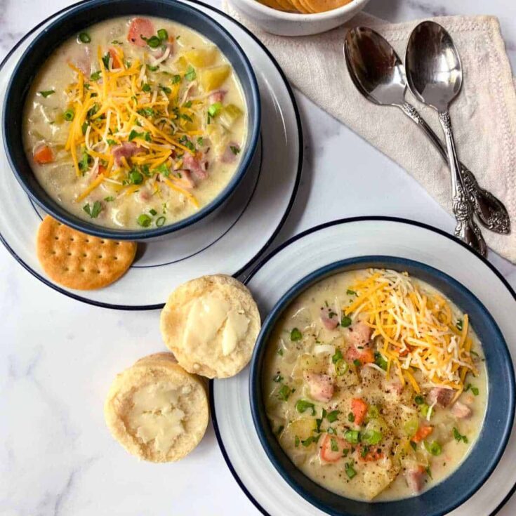 Two bowls of creamy ham and potato soups