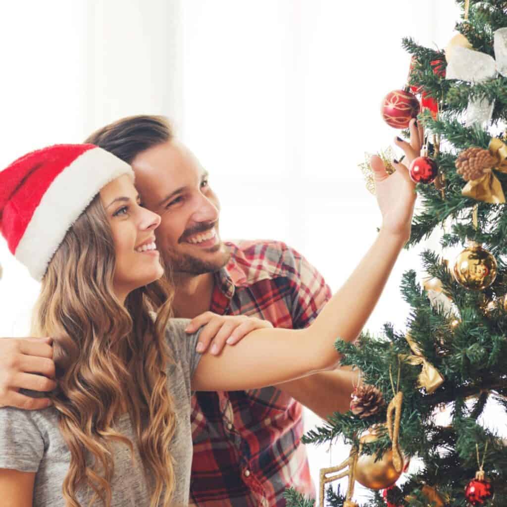 Couple decorating a Christmas tree together.