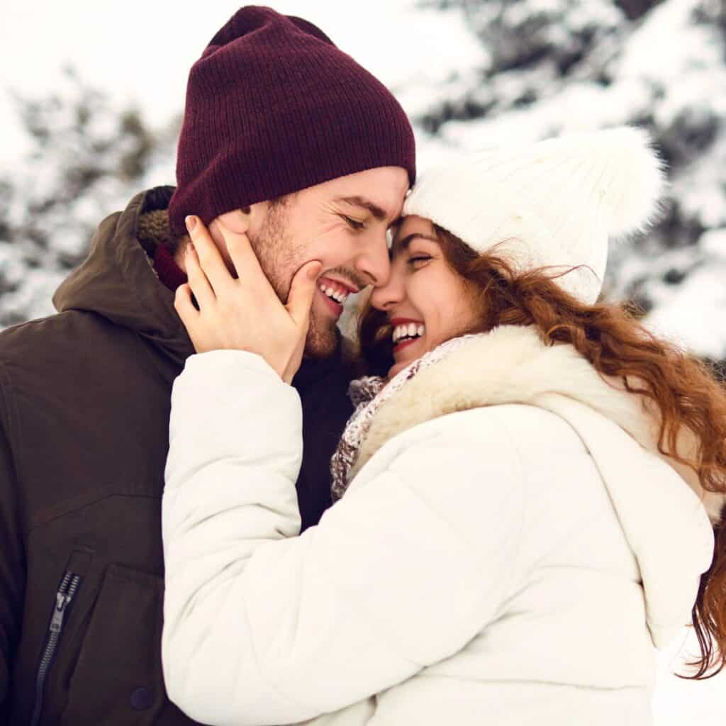 A happy couple playing around the snow, while asking each other these winter would you rather questions