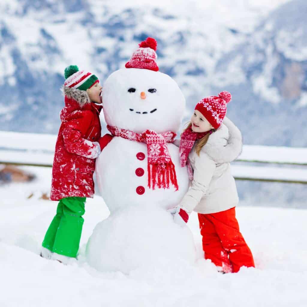 Two kids building a snowman.
