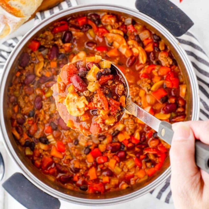 A person scooping a classic beef chili